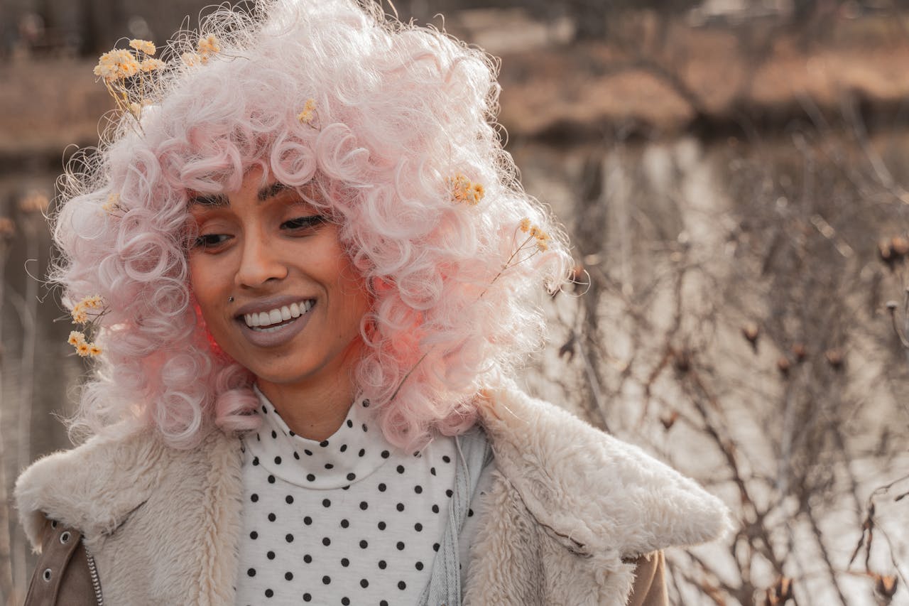 Smiling woman with a pink curly wig enjoying a day outdoors in Washington, DC.